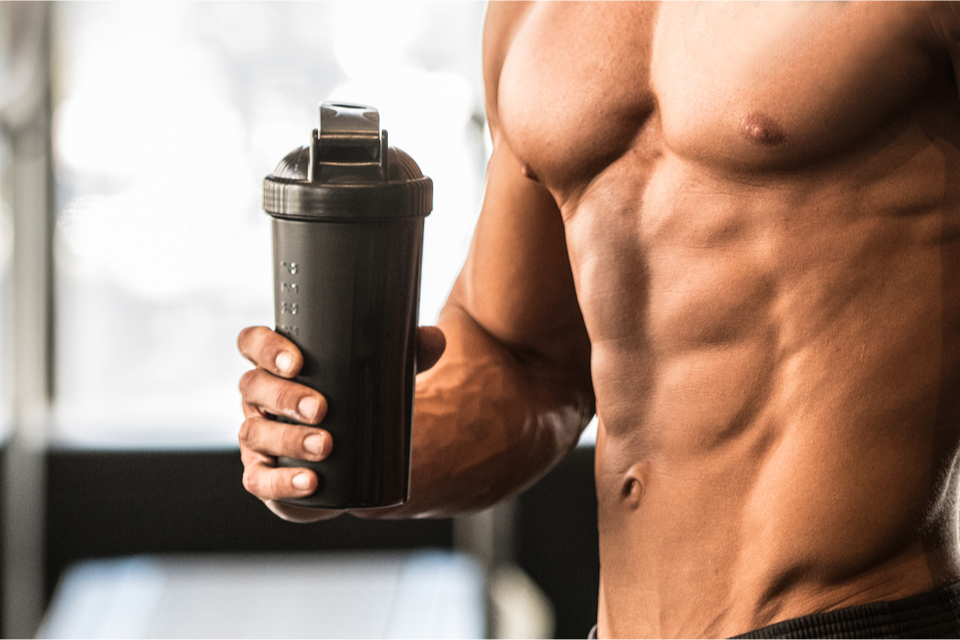 A close of a man's torso with a shaker bottle in hand